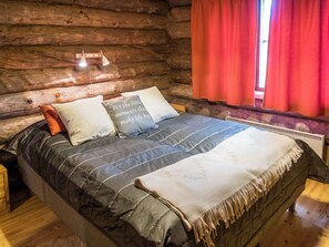 A log cabin bedroom with a bed, pillows, and a window with curtains. - Rukapuro by Interhome (Kuusamo)