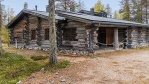 A log cabin with a stone foundation, a wooden porch, and a chimney.