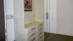 A room with a white wardrobe, a beige bench, and a framed floral artwork on the wall. - Allod Park Haus C E03 by Interhome (Davos)