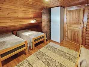 A cabin with two wooden beds, a brick fireplace, a white wardrobe, and a wooden door. - Kuusela by Interhome (Soini)