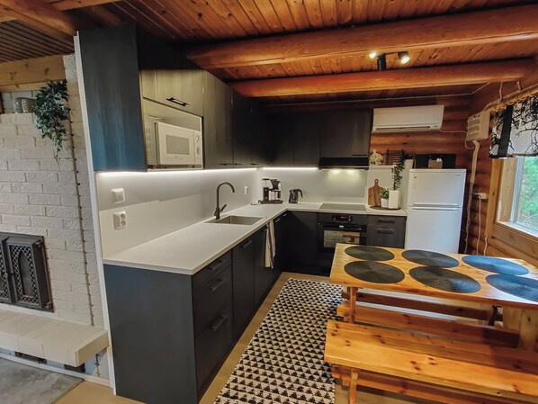 A modern kitchen with a central island, built-in appliances, and a wooden ceiling. - Kuusela by Interhome (Soini)