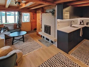 A cozy cabin interior with a living area, a fireplace, and a kitchen. - Kuusela by Interhome (Soini)