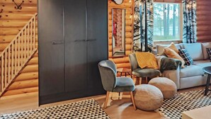 A log cabin interior with a staircase, a sofa set, a round table, and a mirror.