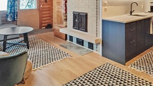 A cozy log cabin interior with a fireplace, a dining area, and a kitchen with modern appliances.
