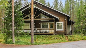 Une cabane avec une façade en bois, de grandes fenêtres et une véranda.