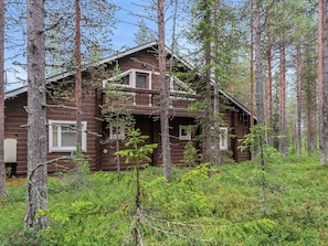 A two-story log cabin with a balcony, surrounded by dense forest. - Artturi by Interhome (Kittilä)