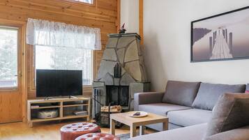 A cozy living room with a stone fireplace, a television, a sofa, and a coffee table.