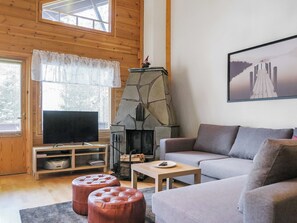 A cozy living room with a stone fireplace, a television, a sofa, and a coffee table.