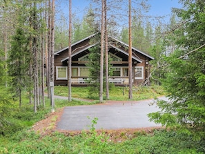 A cabin with a porch, surrounded by tall trees and a clear sky. - Artturi by Interhome (Kittilä)
