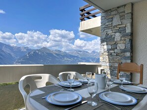 Une table dressée pour le dîner, avec vue sur la montagne, un mur en pierre et un plafond en bois.