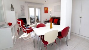 A modern living room with a white dining table, red chairs, a sofa, and a TV. - Playsol by Interhome (Calpe/Calp)