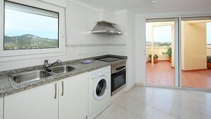 A modern kitchen with a built-in washing machine, a large window, and a view of the city. - Playsol by Interhome (Calpe/Calp)