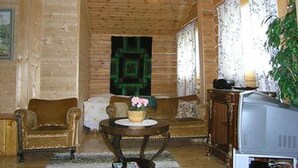 Una habitación acogedora con paredes de madera, un sofá, una mesita con una planta y un televisor.