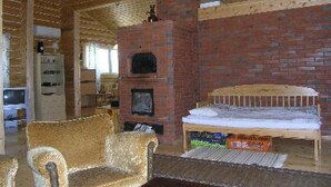 Una habitación acogedora con techo de madera, chimenea de ladrillo, sofá y cama.