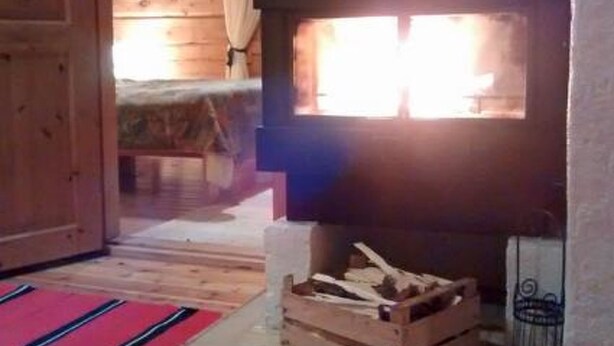 A wooden cabin interior with a fireplace, a bed, and a window. - Karpalo by Interhome (Kittilä)