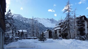 Un villaggio montano innevato con edifici, alberi e cielo sereno.