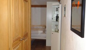 Una stanza con una porta in legno, un letto, un armadietto bianco con vetrate e un quadro appeso al muro.