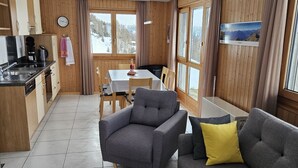 Una sala de estar moderna con un sofá gris, una mesa de centro de madera y un comedor con mesa y sillas.