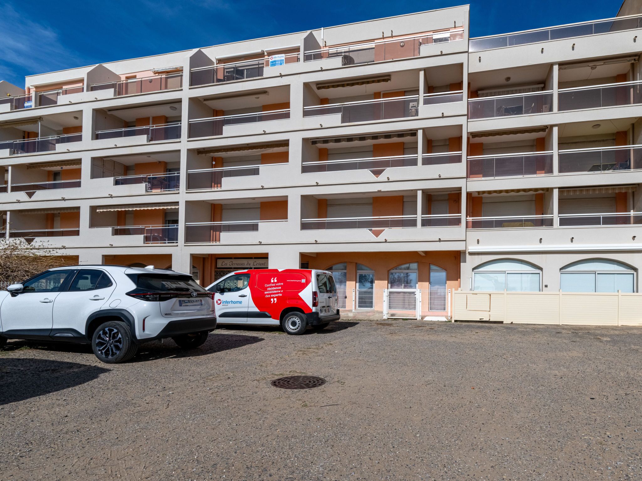 A multi-story hotel with balconies and a parking area.
