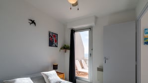 Ein Schlafzimmer mit Bett, Nachttisch, Fenster und Tür.