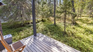 A wooden deck with a chair and a table, overlooking a forested area.