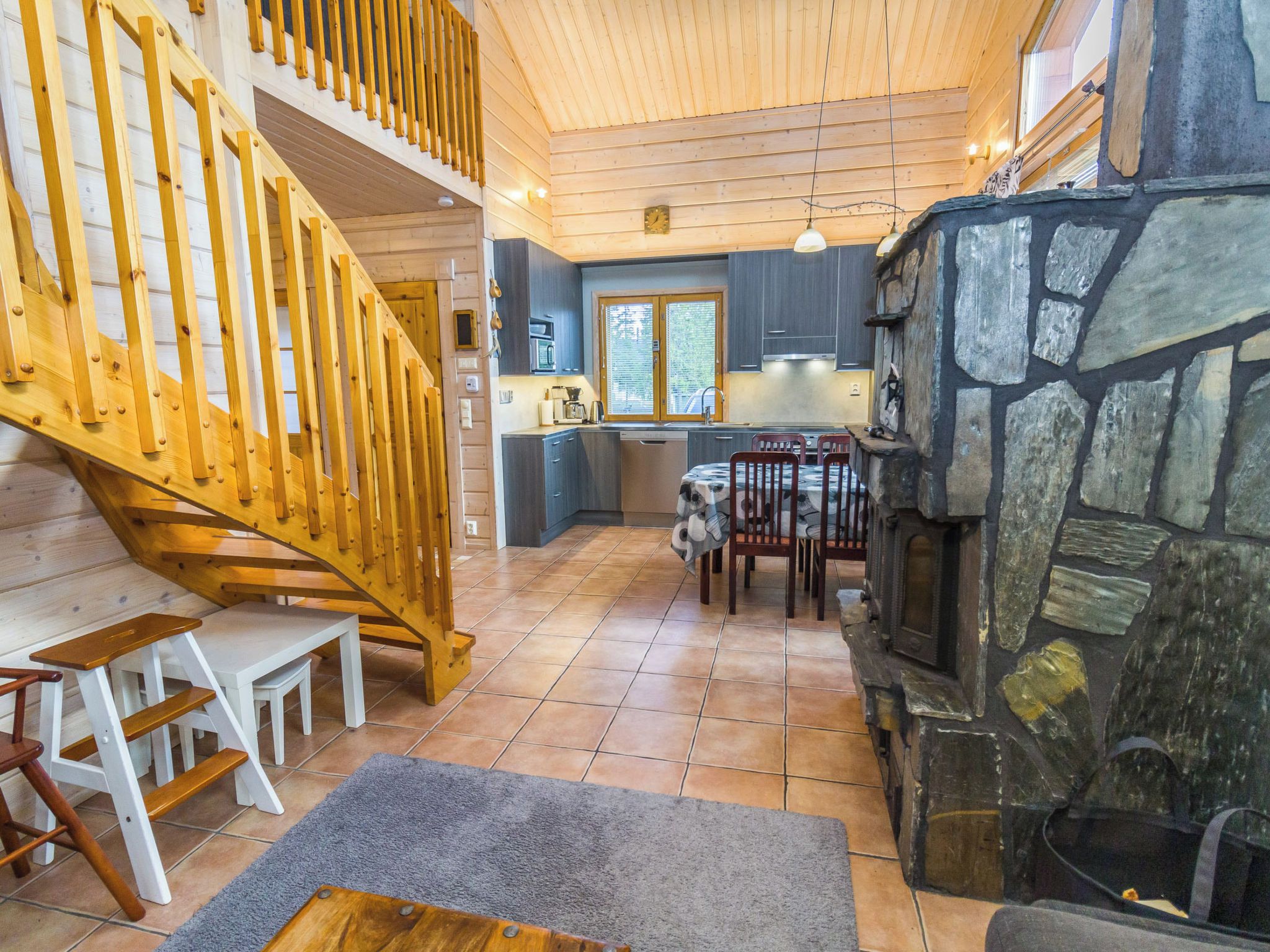 Un intérieur en bois avec un escalier, une cuisine et une cheminée en pierre.