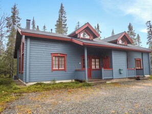 A two-story house with a porch, red trim, and a gravel driveway.