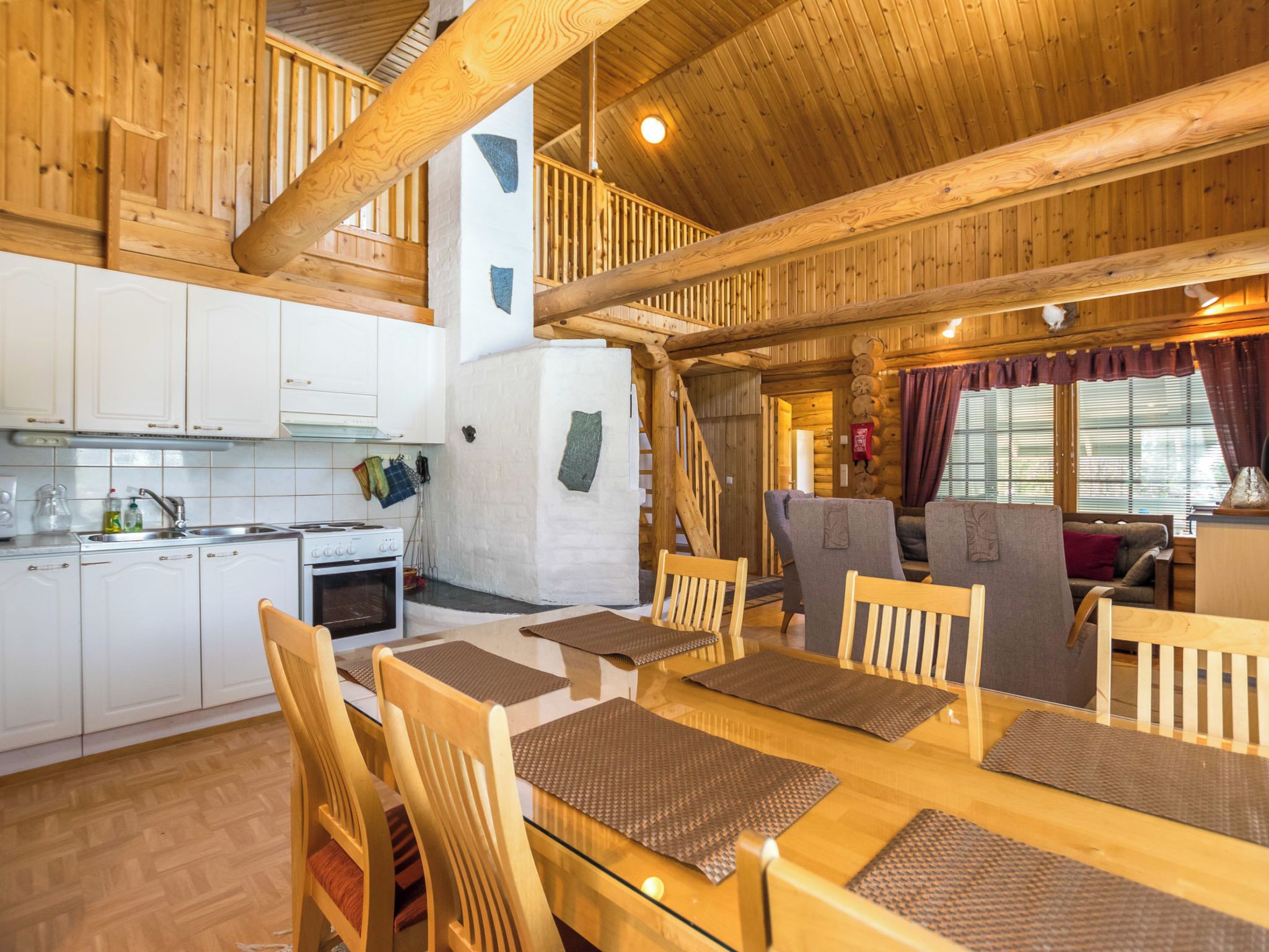 A wooden interior with a kitchen, dining area, and a staircase.
