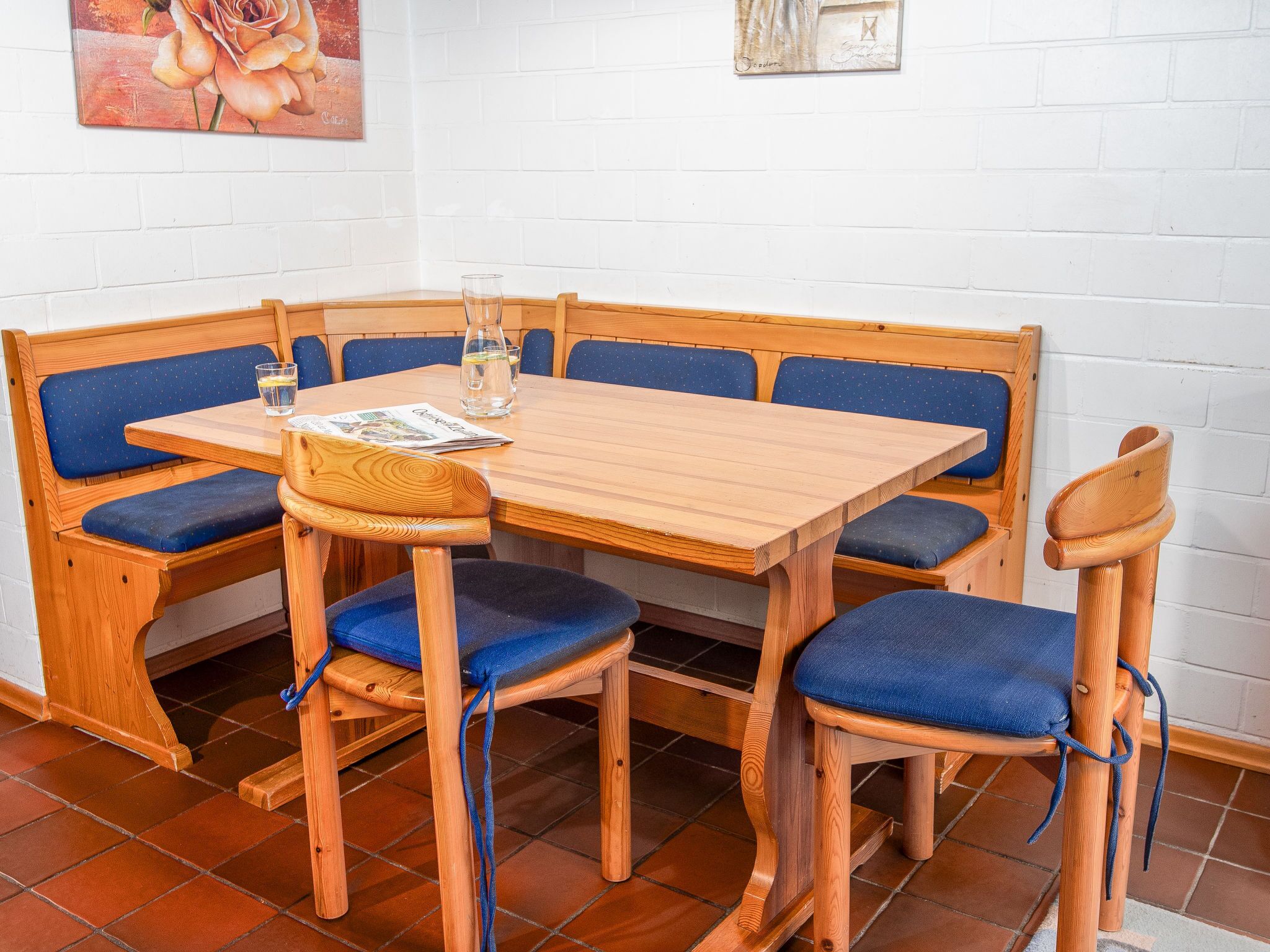 Een eethoek met een houten tafel en blauwe, gewatteerde banken.