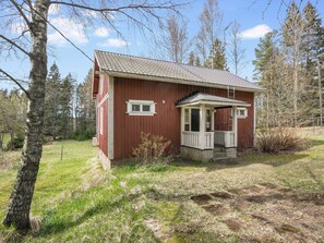 A small, single-story wooden cabin with a porch, surrounded by trees and grass. - Mäkitupa by Interhome (Salo)