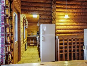 A wooden cabin interior with a refrigerator, wooden walls, and a ladder. - Oloskammi 5 by Interhome (Muonio)