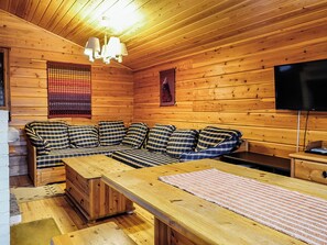 A cozy log cabin interior with a sofa, a wooden table, and a television. - Oloskammi 5 by Interhome (Muonio)