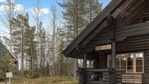 Eine Blockhütte mit Veranda, umgeben von einem Wald.
