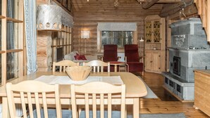 Ein gemütliches Blockhaus-Interieur mit einem Holzespeisetisch, Stühlen, einem Kamin und einem großen Fenster.