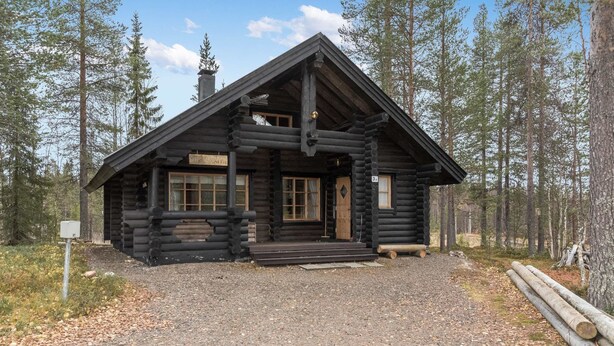Eine Blockhütte mit Veranda, großen Fenstern und einem Schornstein.