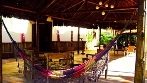 A hammock under a thatched roof, wooden furniture, and a fire extinguisher. - Pousada Grande Rio (Pirapora)