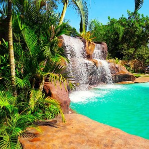 A waterfall cascading into a turquoise pool surrounded by lush greenery and rocks.
