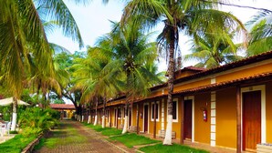 A row of yellow buildings with palm trees in front. - Pousada Grande Rio (Pirapora)