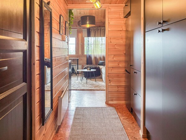 Un couloir intérieur en bois comprenant un coin repas, un canapé et un réfrigérateur.