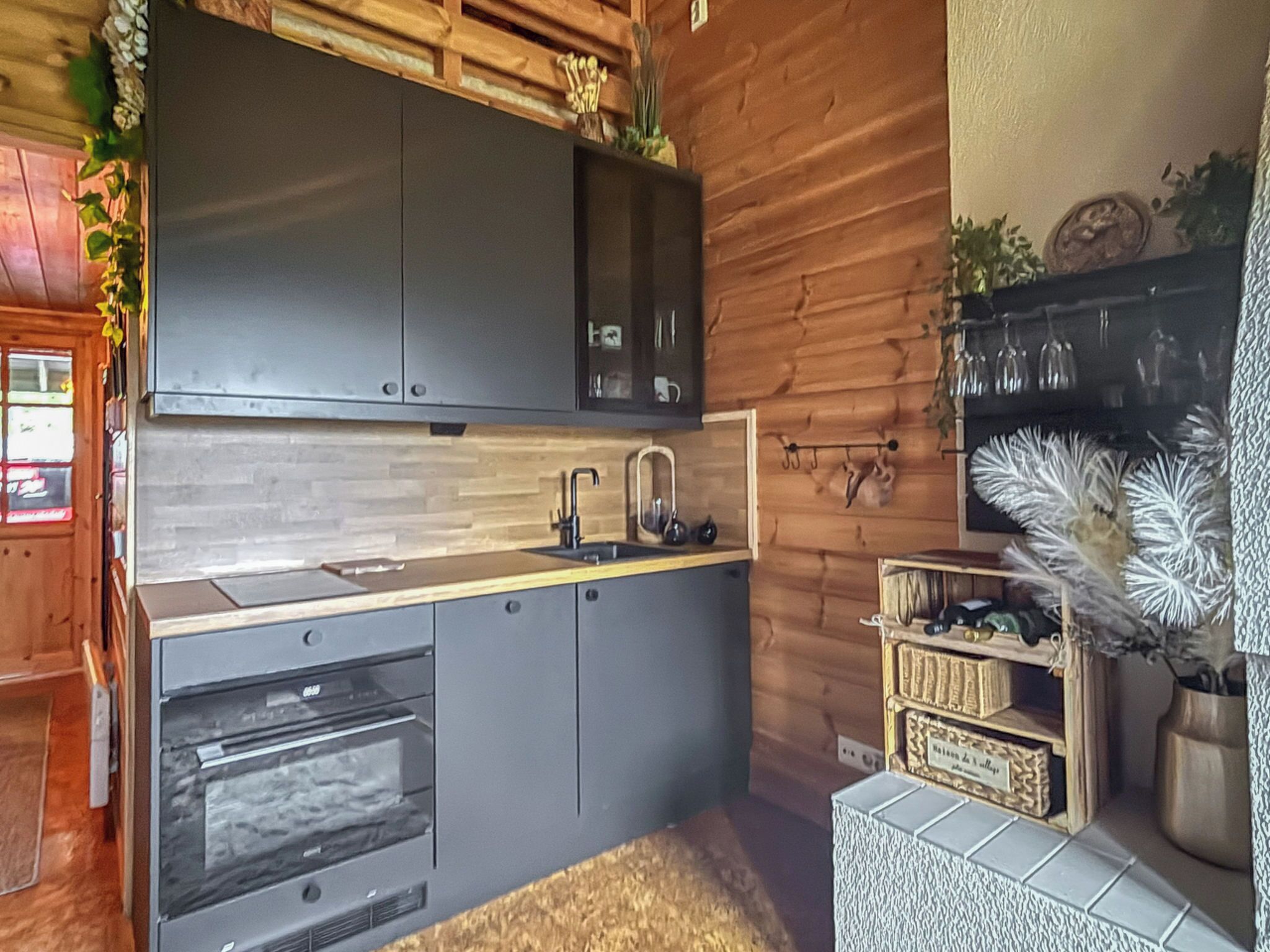 A modern kitchen with dark cabinets, a wooden countertop, and a built-in oven.