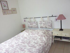 Una camera da letto con un letto, un comodino, una lampada e decorazioni alle pareti.
