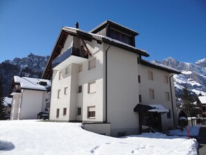 Un edificio a più piani con una seggiovia, circondato da montagne innevate.