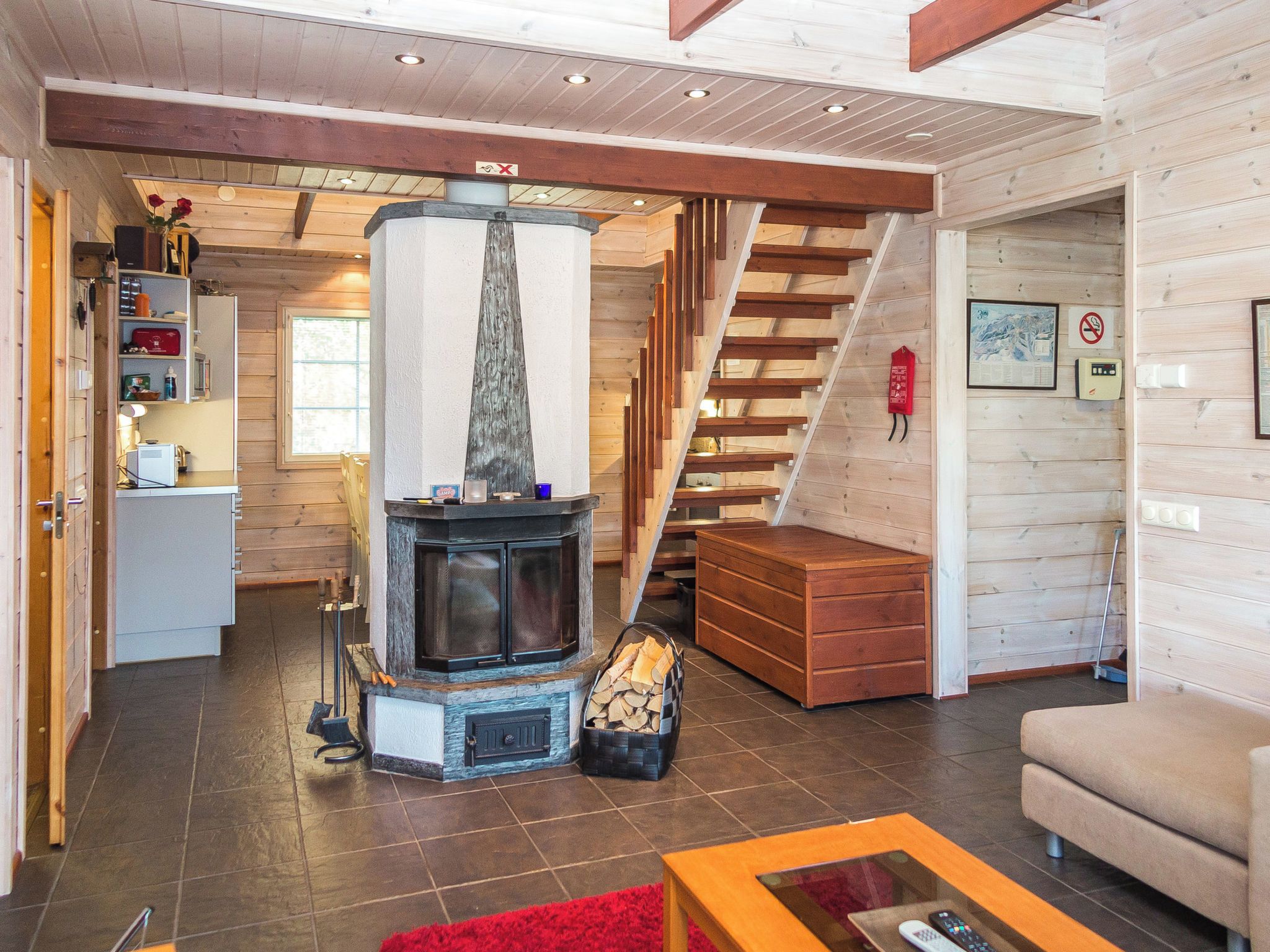 A cozy living room with a fireplace, wooden walls, a staircase, and a sofa.