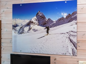 A photograph of a mountain landscape with a person hiking, mounted on a wall. - Alppituulahdus by Interhome (Nilsiä)