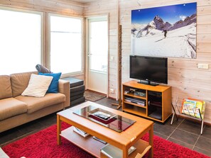 A living room with a sofa, a coffee table, a television on a wooden stand, and a bookshelf. - Alppituulahdus by Interhome (Nilsiä)