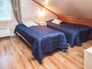 A room with two beds, wooden walls, a sloped ceiling, and a window with blinds. - Alppituulahdus by Interhome (Nilsiä)