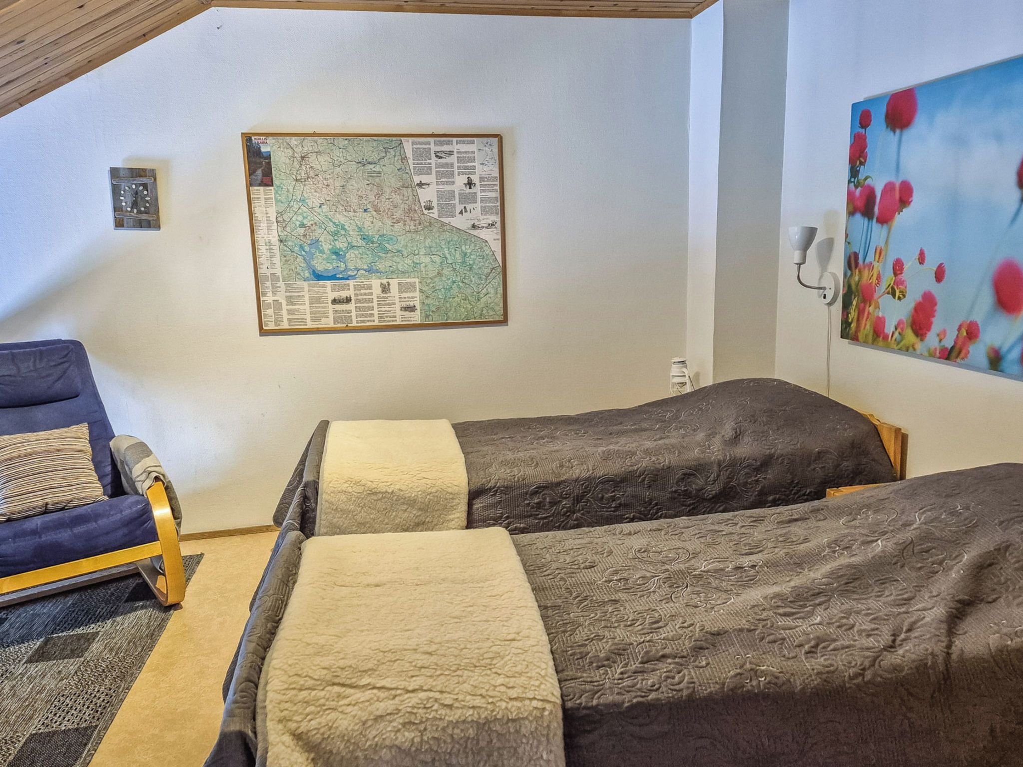 Una habitación con dos camas, un mapa en la pared, un sofá y un cuadro.