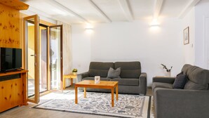 A modern living room with a grey sofa, a wooden coffee table, and a TV on a wooden cabinet. - Residenza Chesa Margun 23-5 by Interhome (Silvaplana-Surlej)