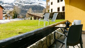 A patio with outdoor seating, a mountain view, and a building with a yellow facade. - Residenza Chesa Margun 23-5 by Interhome (Silvaplana-Surlej)