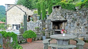 Ein Steinhaus mit Kamin, Sitzgelegenheiten im Freien und Blumentöpfen.